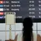 Seorang penumpang melihat papan elektronik yang menampilkan pembatalan penerbangan setelah gunung berapi Lewotobi Laki-Laki meletus di Bandara Internasional Ngurah Rai di Tuban dekat Denpasar, Bali, pada 18 Juni 2025. (SONNY TUMBELAKA/AFP)