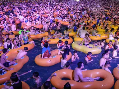 Foto pada 15 Agustus 2020 memperlihatkan orang-orang menonton pertunjukan musik sambil bermain air di sebuah taman air atau water park di Wuhan, provinsi Hubei, China. Mereka berpesta saat Wuhan kembali ke kehidupan normal setelah sempat terdampak parah oleh COVID-19. (STR/AFP)