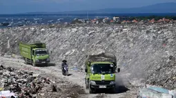 Namun, jadwalnya dibatasi hanya dua kali seminggu dari pukul 08.00 hingga 20.00 WITA. Tampak dalam foto, kendaraan melintas di dekat tumpukan sampah di Tempat Pembuangan Akhir (TPA) Suwung berlatar belakang salah satu lokasi wisata di Denpasar, Bali, pada Jumat 17 April 2026. (SONNY TUMBELAKA/AFP)