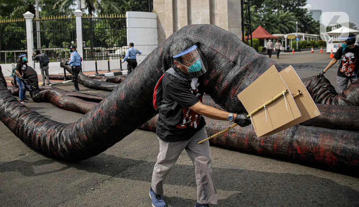 Aktivis Greenpeace saat menggelar aksi di depan Gedung DPR RI, Jakarta, Selasa (5/10/2021). Dalam aksinya, mereka membawa gurita raksasa sebagai simbol oligarki serta menyerukan kepada pemerintah agar serius mengatasi pandemi dan memberantas korupsi energi. (Liputan6.com/Faizal Fanani)