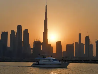 Matahari terbenam di belakang bangunan tertinggi di dunia Burj Khalifa dan gedung-gedung bertingkat lainnya, di Dubai, Uni Emirat Arab pada Sabtu (12/9/2020). (Photo by Karim SAHIB / AFP)