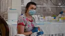 Perawat merawat bayi yang baru lahir dari skema ibu pengganti (surrogate mother) di Hotel Venice, Kiev, Ukraina, 15 Mei 2020.  Menurut Ombudsman Ukraina, jika karantina diperpanjang maka jumlah bayi yang telantar bisa mencapai ribuan. (Sergei SUPINSKY/AFP)