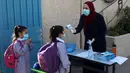 Seorang pelajar menjalani pemeriksaan suhu tubuh di sekolah pada hari pertama tahun ajaran baru di kamp pengungsi Al-Amari di Kota Ramallah, Tepi Barat (6/9/2020). Pelajar Palestina memulai tahun ajaran baru setelah belajar di rumah selama enam bulan akibat Covid-19. (Xinhua/Nidal Eshtayeh)