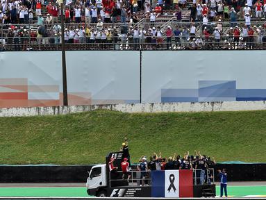 Para pebalap F1 mengikuti parade dengan truk yang dipasangi bendera Prancis sebagai tanda duka terhadap para korban serangan teroris sebelum dimulainya start F1 GP Brasil di Sirkuit Interlagos, Sao Paulo, Brasil, (15/11/2015). (AFP Photo/Nelson Almeida)