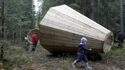 Pengunjung bermain di dekat megafon raksasa dari kayu buatan sekelompok mahasiswa arsitektur interior di dalam hutan Estonia, 28 September 2015. Megafon ini dibuat untuk mendengarkan suara hutan dan mahluk yang tinggal di dalamnya (REUTERS/Ints Kalnins)