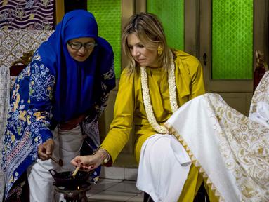Ratu Maxima dari Belanda (kanan), dalam kapasitasnya sebagai Advokat Khusus Sekretaris Jenderal PBB untuk Keuangan Inklusif untuk Pembangunan (UNSGSA), mencoba membatik di Kampung Batik Laweyan, Surakarta, Jawa Tengah, pada Selasa 25 November 2025. Ratu Belanda, Maxima Zorreguieta Cerruti, mengunjungi Kampung Batik Laweyan, Surakarta, Jawa Tengah, Selasa (25/11/2025). (DEVI RAHMAN/AFP)