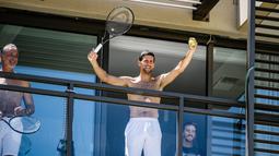 Petenis pria peringkat satu dunia, Novak Djokovic menyapa penggemarnya disela-sela menjalani latihan dari balkon hotel, Adelaide, Australia, Rabu (20/1/2021). (Foto: AFP/Morgan Sette)
