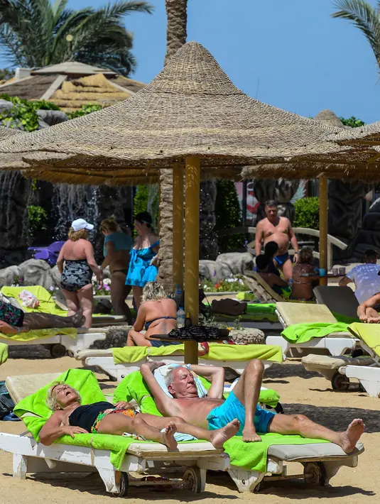 Wisatawan bersantai sembari menikmati mahatari di pantai kota wisata Laut Merah Mesir, Hurghada pada 3 April 2019. Selain Piramida atau Sphinx di Giza atau modernnya ibu kota di Kairo, turis juga bisa datang ke kawasan resor Hurghada. (Mohamed el-Shahed / AFP)