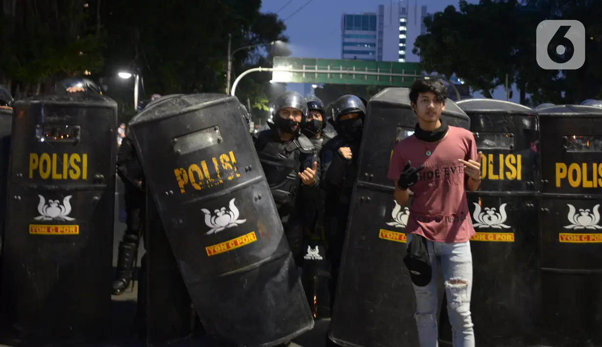 Seorang pendemo foto bersama anggota kepolisian saat aksi menolak Omnibus Law UU Cipta Kerja di kawasan Patung Kuda, Jakarta, Selasa (20/10/2020).  Anggota Marinir membubarkan dan mengawal pulang massa pendemo  ke rumah masing-masing. (merdeka.com/Imam Buhori)
