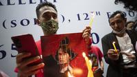 Warga Myanmar yang tinggal di Thailand memegang foto pemimpin Myanmar Aung San Suu Kyi dan menyalakan lilin saat protes di depan Kedutaan Besar Myanmar di Bangkok, Thailand, Kamis (4/2/2021). Warga memprotes kudeta militer yang terjadi Myanmar. (AP Photo/Sakchai Lalit)