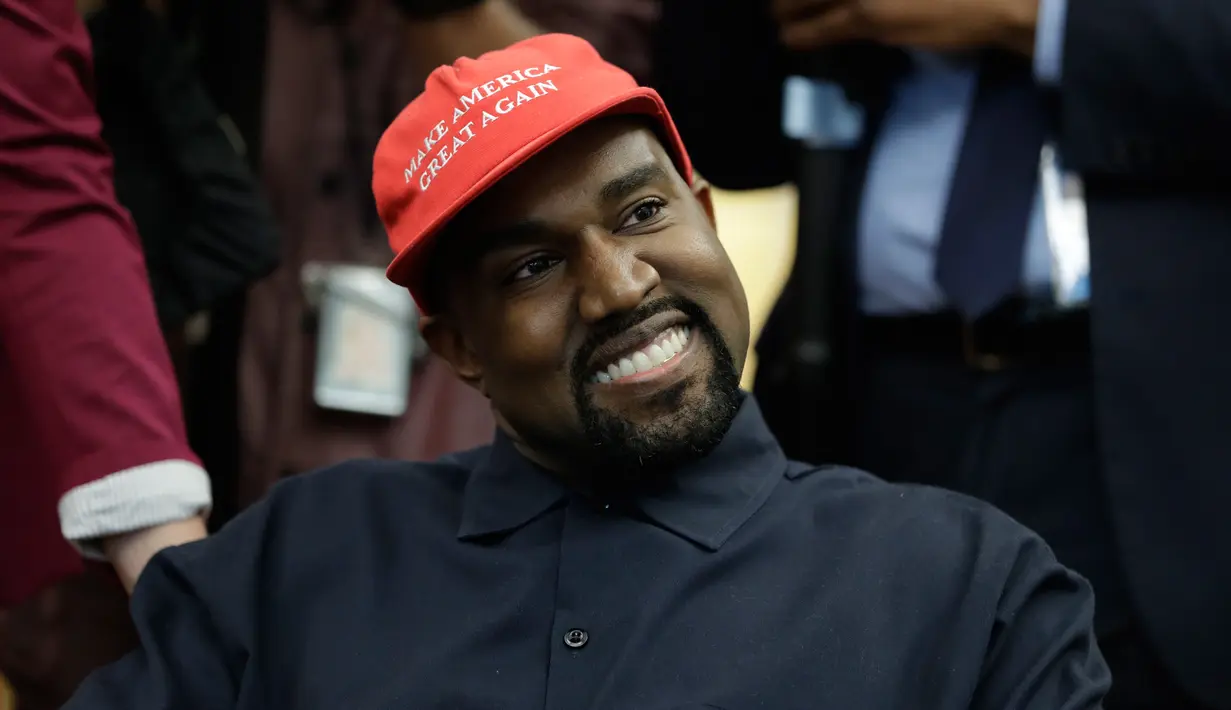 Rapper Kanye West saat bertemu dengan Presiden AS, Donald Trump di Oval Office, Gedung Putih, Kamis (11/10). West mengenakan topi bertuliskan slogan yang kerap digaungkan Trump, yakni "Make America Great Again". (AP/Evan Vucci)