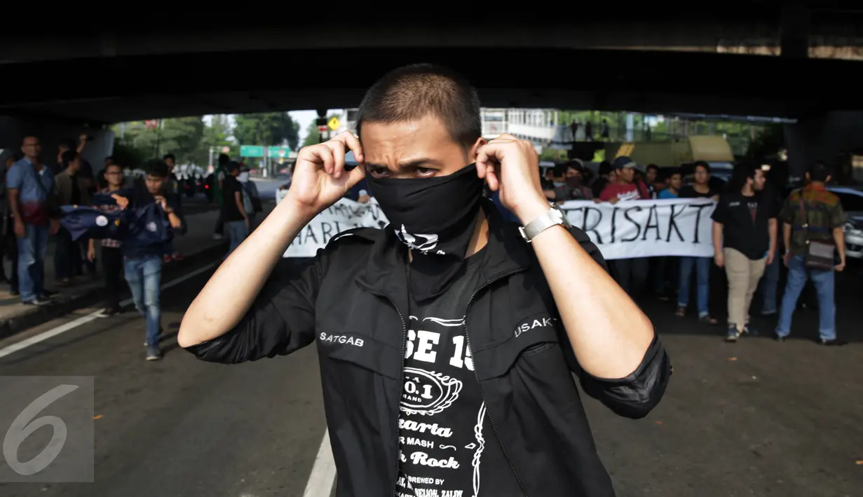 Seorang mahasiswa Trisakti memakai penutup mulut saat menggelar aksi protes dengan menutup Jalan Kyai Tapa, Jakarta Barat, Jumat (2/9). Aksi itu mendesak penyelesaian kisruh masalah internal antara rektorat dengan yayasan kampus (Liputan6.com/Johan Tallo)