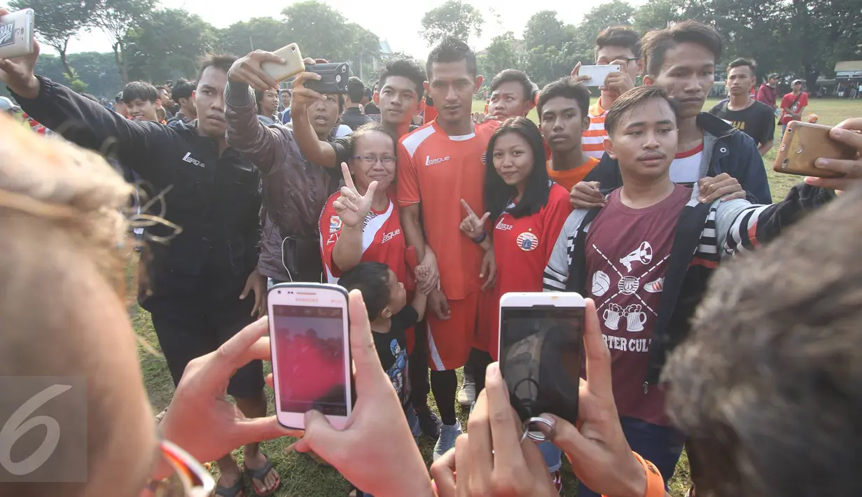 The Jakmania berfoto bersama pemain seusai sesi latihan di Lapangan Banteng, Jakarta, Selasa (11/4). Sesi latihan tersebut dimanfaatkan ratusan The Jakmania untuk sekadar berfoto dan menyapa para pemain. (Liputan6.com/Immanuel Antonius)