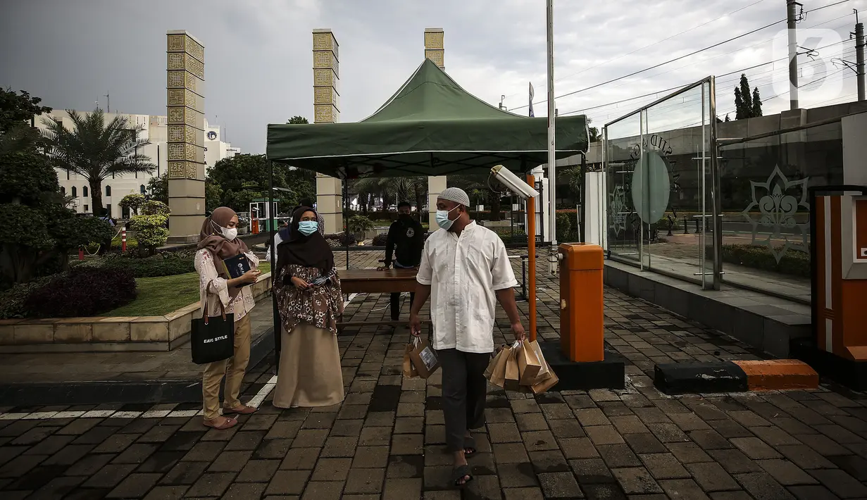 Petugas membawa takjil untuk dibagikan kepada pengendara di Kompleks Masjid Al-Azhar, Jakarta, Kamis (15/4/2021). Pengelola masjid menyiapkan 500 bungkus takjil setiap harinya untuk pengendara yang dibagikan dengan sistem drive thru untuk mencegah penyebaran COVID-19. (Liputan6.com/Johan Tallo)