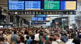 Para penumpang berkumpul di sekitar layar monitor yang menunjukkan jadwal keberangkatan dan kedatangan di stasiun kereta Gare Montparnasse di Paris pada tanggal 26 Juli 2024. (Thibaud MORITZ / AFP)