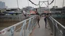 Seorang anak melompat dari atas jembatan dan berenang di aliran kali besar Banjir Kanal Barat, Jakarta, Sabtu (11/3). Minimnya pengawasan orang tua membuat mereka bermain di tempat berbahaya dan mengancam keselamatan. (Liputan6.com/Faizal Fanani)