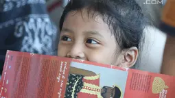 Seorang anak tertawa saat menyaksikan aksi pementasan cerita sejarah pertempuran pasukan Mataram di Museum Nasional Indonesia, Jakarta, Minggu (29/4). Dongeng tersebut berkisah penyerangan Sultan Agung ke Batavia. (Liputan6.com/Helmi Fithriansyah)