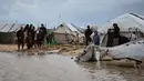 Hujan deras dan angin kencang merendam tenda-tenda para pengungsi, dan memperburuk krisis kemanusiaan yang sudah ada. Tampak dalam foto, warga Palestina berjalan melewati area yang tergenang banjir di kamp tenda sementara setelah hujan lebat di Kota Gaza, Kamis, 26 Maret 2026 (AP Photo/Jehad Alshrafi)