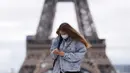 Seorang perempuan yang mengenakan masker berjalan-jalan di Istana Trocadero tak jauh dari Menara Eiffel di Paris, 10 Juli 2020. Dengan 25 kematian baru yang dicatat dalam 24 jam terakhir, jumlah kematian terkait corona COVID-19 di Prancis naik menjadi 30.004 pada Jumat (10/7). (Xinhua/Gao Jing)