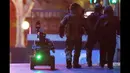 Polisi mengenakan pakaian lapis baja berjalan dengan robot menuju Kafe Lindt di Martin Place, Sydney (16/12/2014). Lebih dari 16 jam beberapa orang menjadi korban penyanderaan yang terjadi di Kafe Lindt.(REUTERS/Jason Reed)