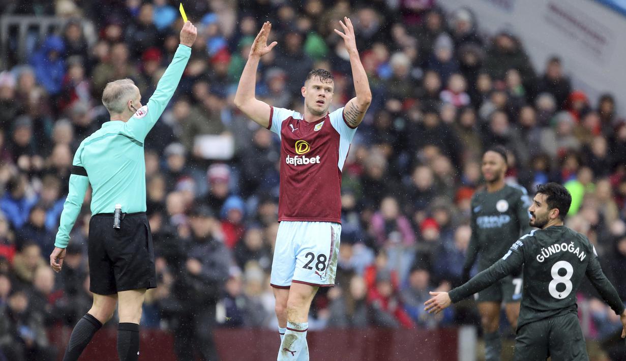 Pemain Burnley, Kevin Long (tengah) menerima kartu kuning dari wasit Martin Atkinson pada lanjutan Premier League di Turf Moor  Stadium, Burnley, (3/2/2018). Burnley tahan Manchester City 1-1. (Richard Sellers/PA via AP)