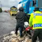 Personel Polres Pelalawan membantu mendorong sepeda mootor warga yang terjebak banjir. (Liputan6.com/M Syukur)