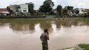 Petugas berdiri di bantaran Sungai Ciliwung di kawasan Rawajati,  Jakarta, Selasa (25/2/2020). Adanya seorang warga yang hanyut saat berenang di tengah luapan Sungai Ciliwung tersebut mengundang perhatian warga serta petugas yang mencari keberadannya. (Liputan6.com/Immanuel Antonius)