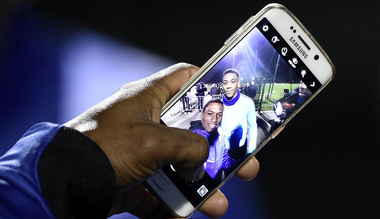 Seorang penggemar berfoto bersama striker Prancis, Anthony Martial, dalam sesi latihan timnas Prancis di Clairefontaine-en-Yvelines, Prancis, (10/11/2015). (AFP Photo/Franck Fife)