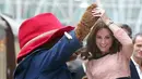 Kate Middleton asyik berdansa dengan seorang aktor yang mengenakan kostum Paddington di stasiun kereta Paddington, London, Senin (16/10). Duchess of Cambridge itu tampak menikmati momen dansa dengan Beruang Paddington. (Chris J Ratcliffe/AFP)