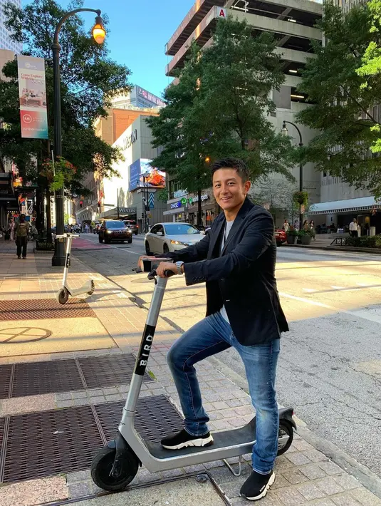 Pose lucu nan menggemaskan Rio Haryanto pakai kaus putih yang ditumpuknya dengan jas hitam, dipadu mengenakan celana jeans dan sneakers hitam. [Foto: Instagram/rharyantoracing]