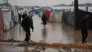 Puluhan hingga ratusan tenda pengungsi Palestina di wilayah tersebut terendam banjir. Tampak dalam foto, warga Palestina berjalan melewati kamp tenda yang terendam banjir setelah hujan lebat di Deir al-Balah, Jalur Gaza, Kamis 11 Desember 2025. (AP Photo/Abdel Kareem Hana)