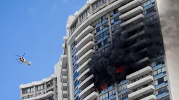 Petugas mengerahkan helikopter untuk membantu proses evakuasi kebakaran yang terjadi di apartemen Marco Polo, Honolulu (14/7). Hingga saat ini tim pemadam kebakaran masih terus berusaha menjinakkan api di apartemen tersebut. (AP Photo / Marco Garcia)