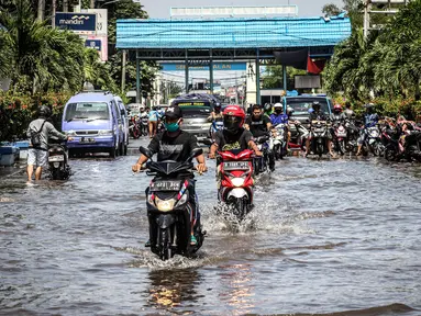 Kendaraan bermotor melintasi jalan yang tergenang air rob (banjir pasang air laut) di Kawasan Pasar Ikan Muara Baru, Jakarta, Kamis (4/6/2020). Banjir rob di Pelabuhan Muara Baru tersebut terjadi akibat cuaca ekstrem serta pasangnya air laut. (Liputan6.com/Faizal Fanani)