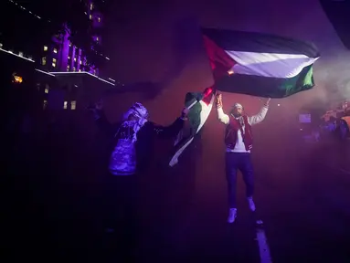 Orang-orang mengibarkan bendera Palestina saat bom asap diledakkan dalam demonstrasi mendukung warga Palestina di Vancouver, British Columbia, Kanada, Kamis (19/10/2023). Unjuk rasa untuk mendukung warga Palestina dimulai di Balai Kota Vancouver dan berlanjut ke beberapa bagian kota. (Darryl Dyck/The Canadian Press via AP)
