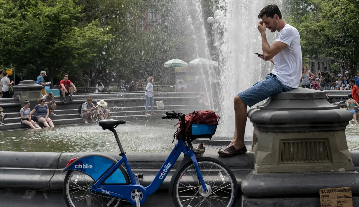 Sejumlah warga  mendinginkan diri di dekat air mancur saat siang hari yang panas di Washington Square Park di New York City (17/7/2019). Gelombang panas besar akan mempengaruhi hampir dua pertiga dari Amerika Serikat, dengan Pantai Timur dan Midwest. (AFP Photo/Drew Angerer)