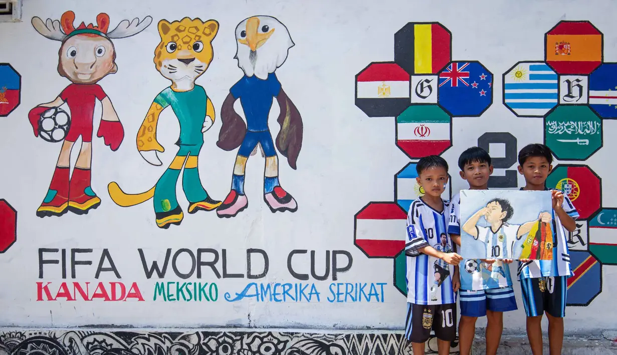 Anak-anak berpose di depan mural yang menampilkan turnamen sepak bola Piala Dunia 2026 di Polewali Mandar, Sulawesi Barat, Kamis 11 Juni 2026. (Muhammad SALIM/AFP)