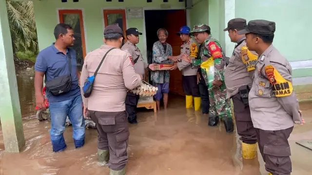 Kapolsek Siak Kecil Ipda Eko Wahyu bersama personel dan TNI serta aparatur desa menyerahkan bantuan sembako kepada korban bencana banjir.