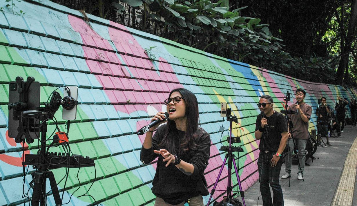 Beberapa platform media sosial seperti TikTok, YouTube, dan Instagram bertransformasi menjadi panggung virtual di mana penyanyi dapat langsung menjangkau jutaan pendengar tanpa melalui agensi atau pihak lain. Tampak dalam foto, para penyanyi dalam jaringan (daring/online) menggunakan dinding berwarna-warni sebagai latar belakang tampil untuk menarik penonton agar memberikan donasi digital selama siaran langsung mereka di situs media sosial, Bandung, Jawa Barat, pada Jumat 8 Mei 2026. (Timur Matahari/AFP)