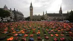 Jaket pelampung dipajang seperti sebuah pemakaman umum di dekat Gedung Parlemen London, Senin (19/9).  Sebanyak 2.500 jaket pelampung yang usang ini pernah dipakai para pengungsi yang menyebrang dari Turki ke Pulau Chios, Yunani. (Daniel Leal-Olivas/AFP)