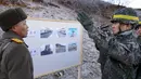Tentara Korea Selatan berbincang dengan tentara Korea Utara  sebelum melintasi Garis Demarkasi Militer di Cheorwon, Rabu (12/12). Mereka mulai memeriksa pembongkaran pos-pos penjaga di Zona Demiliterisasi. (HANDOUT/AFP/SOUTH KOREAN DEFENCE MINISTRY)