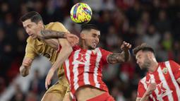 Pemain Barcelona, Robert Lewandowski (kiri) berebut bola dengan pemain Almeria Chumi pada laga lanjutan Liga Spanyol 2022/2023 yang berlangsung di Power House Stadium, Senin (27/02/2023) dini hari WIB. (AFP/Jorge Guerrero)