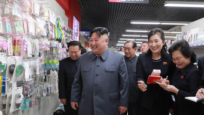 Pemimpin Korea Utara, Kim Jong-un tersenyum saat melihat barang-barang yang dijual di Taesong Department Store di Korea Utara (8/4). (KCNA VIA AFP Photo)