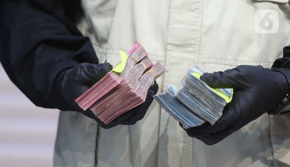 Uang tersebut merupakan bagian dari total Rp 2,7 miliar yang diduga telah diterima Gatut Sunu Wibowo dari permintaan awal sebesar Rp 5 miliar. Tampak dalam foto, tumpukan uang barang bukti terkait Operasi Tangkap Tangan (OTT) Bupati Tulungagung, Gatut Sunu Wibowo, diperlihatkan petugas di Gedung Merah Putih Komisi Pemberantasan Korupsi (KPK), Jakarta, Sabtu (11/4/2026). (Liputan6.com/Helmi Fithriansyah)