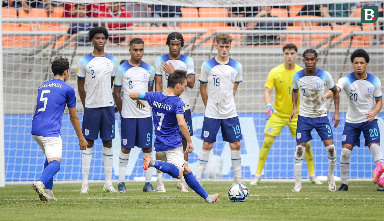 Pemain Timnas Uzbekistan U-17, Lazizbek Mirzaev (tengah), menendang bola dari tendangan bebas yang membuahkan gol saat melawan Timnas Inggris U-17 dalam pertandingan babak 16 besar Piala Dunia U-17 2023 yang berlangsung di Jakarta International Stadium, Jakarta, Rabu (22/11/2023). (Bola.com/Bagaskara Lazuardi)
