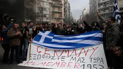 Ratusan Petani membawa bendera Yunani bertuliskan "Germany pay us back now" selama protes petani terhadap perubahan peraturan pensiun yang direncanakan di luar Kementerian Pertanian, Athena, Yunani, Jumat (12/2). (REUTERS/Alkis Konstantinidis)	