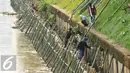 Pekerja memasang turap dari bambu sepanjang 600 meter di Bantaran Kali Ciliwung, Jakarta, Jumat (5/8). Pemasangan tersebut untuk menahan dinding tanah yang kerap longsor. (Liputan6.com/Gempur M Surya)