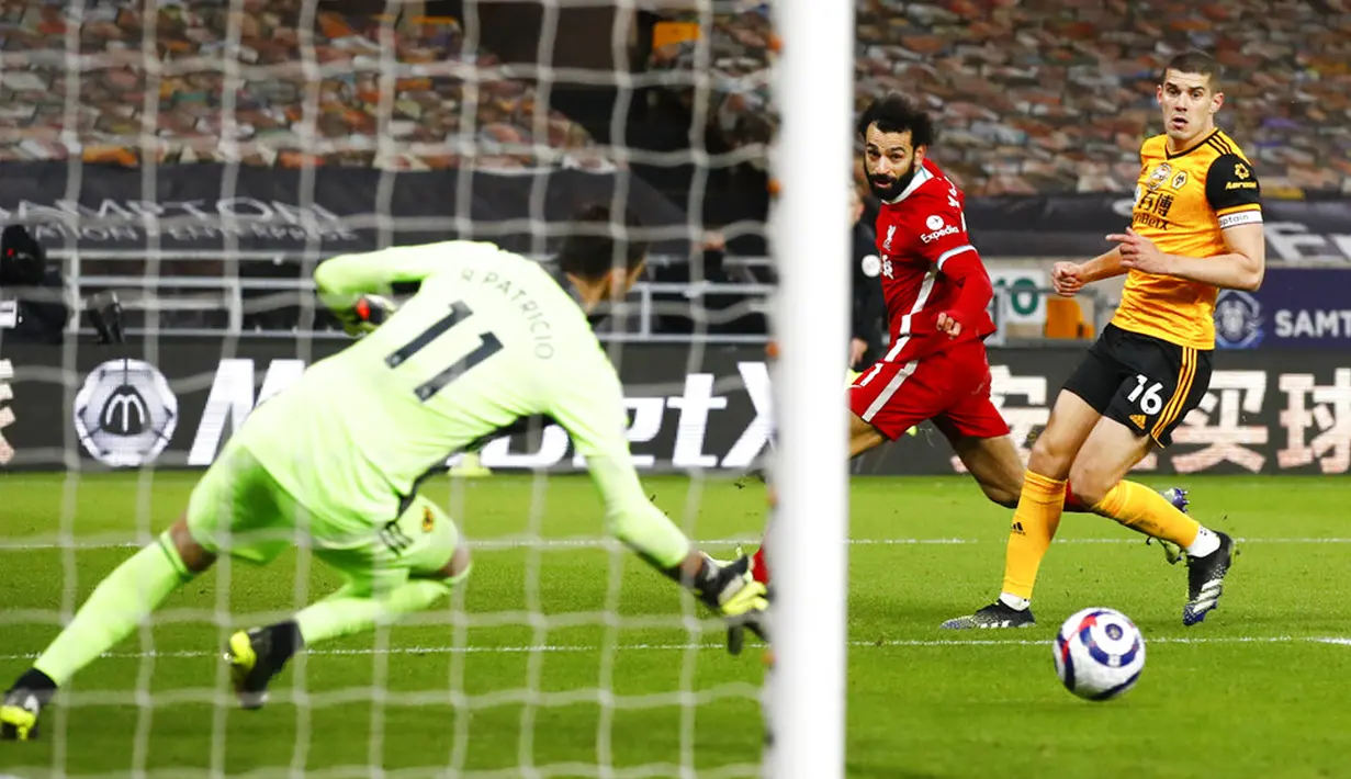 Pemain Liverpool Mohamed Salah (tengah) melepaskan tembakan melebar dari kiper Wolverhampton Wanderers Rui Patricio (kiri) pada pertandingan Liga Inggris di Stadion Molineux, Wolverhampton, Inggris, Senin (15/3/2021). Liverpool menang 1-0. (AP Photo/Jason Cairnduff,Pool)