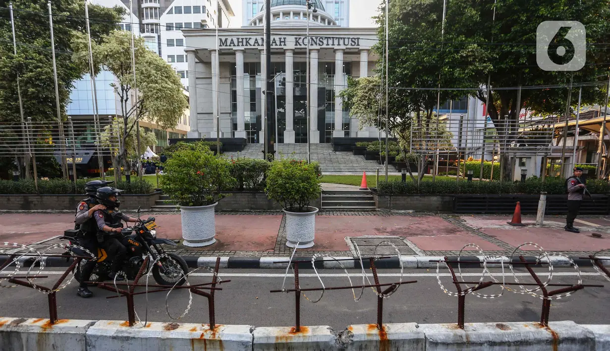 Petugas memasang beton pembatas dengan kawat berduri di halaman depan Gedung Mahkamah Konstitusi (MK) di Jakarta, Senin (25/3/2024). (Liputan6.com/Angga Yuniar)