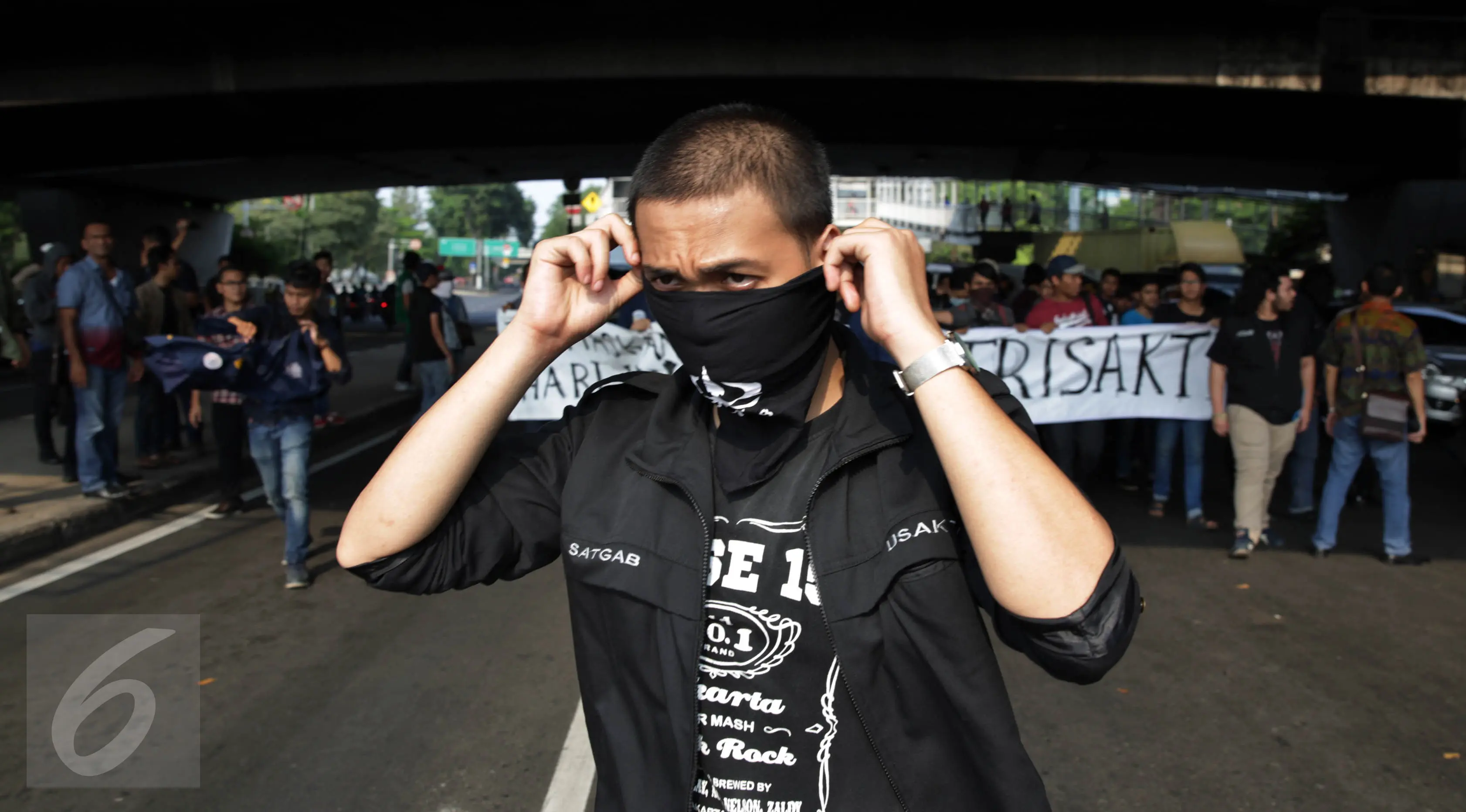 Seorang mahasiswa Trisakti memakai penutup mulut saat menggelar aksi protes dengan menutup Jalan Kyai Tapa, Jakarta Barat, Jumat (2/9). Aksi itu mendesak penyelesaian kisruh masalah internal antara rektorat dengan yayasan kampus (Liputan6.com/Johan Tallo)