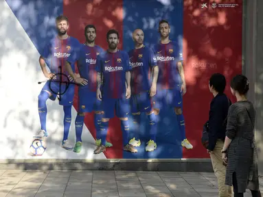 Fans melihat poster pemain Barcelona, Gerard Pique yang dirusak di sebuah toko yang ditutup sebagai bagian dari pemogokan oleh serikat pekerja Catalonia di luar stadion Camp Nou, Barcelona (3/10). (AFP Photo/Josep Lago)